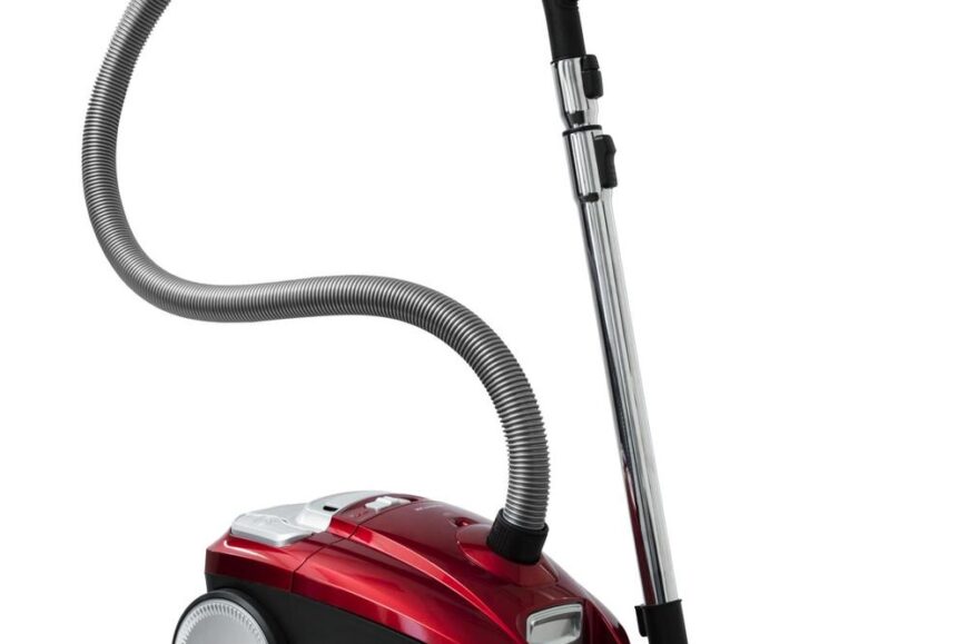 Een stijlvolle rode stofzuiger met een flexibel, gegolfd slang en een metalen buis. De stofzuiger is uitgerust met een stofzuigmond en een grote wieltje aan de onderkant voor gemakkelijke manoeuvreerbaarheid.