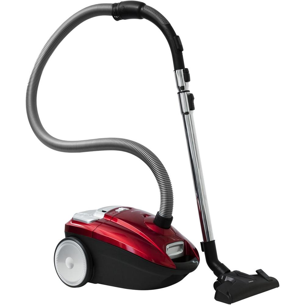 Een stijlvolle rode stofzuiger met een flexibel, gegolfd slang en een metalen buis. De stofzuiger is uitgerust met een stofzuigmond en een grote wieltje aan de onderkant voor gemakkelijke manoeuvreerbaarheid.