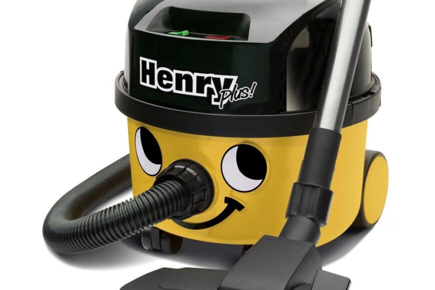 Afbeelding van een vrolijk gele stofzuiger met een zwart bovenstuk, het model "Henry Plus". De stofzuiger heeft een lachend gezicht en is uitgerust met een slang en een zuigmond.