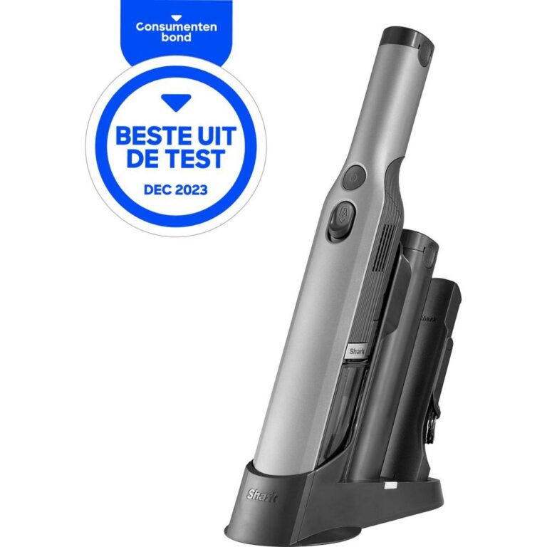 Een zilverkleurige handstofzuiger van het merk Shark, geplaatst in een laadstation. Boven de stofzuiger bevindt zich een label van de Consumentenbond met de tekst "Beste uit de test" en de datum "dec 2023".