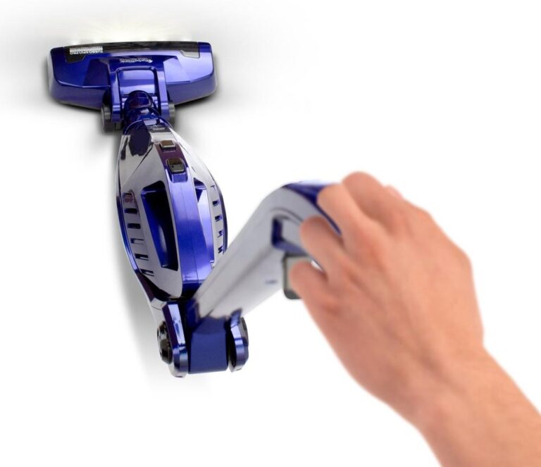 Een hand houdt een handstofzuiger vast met een glanzende paarse behuizing. De stofzuiger heeft een slank ontwerp en een verlicht mondstuk, ideaal voor het snel reinigen van kleine ruimtes.