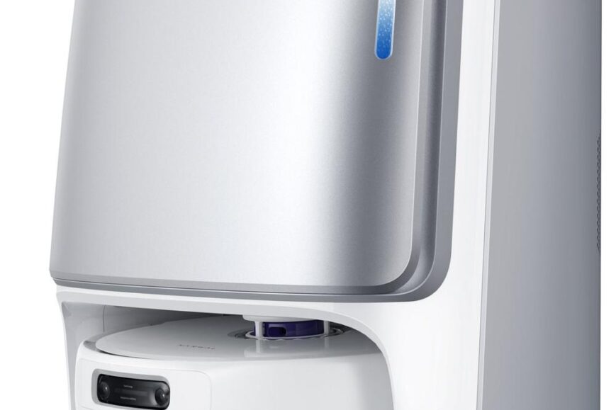 Een stijlvolle robotstofzuiger met een glanzend zilveren ontwerp en een zwarte bedieningspaneel aan de voorkant. Deze afbeelding toont het apparaat van opzij, waardoor de ronde basis en het minimalistische uiterlijk goed zichtbaar zijn.