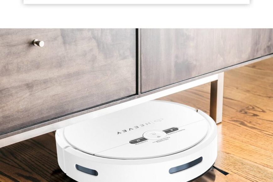 Een witte robotstofzuiger bevindt zich onder een laag meubelstuk op een houten vloer. Boven de stofzuiger staat de tekst "Grondige reiniging" die de functionaliteit benadrukt van het apparaat dat moeilijk bereikbare plekken kan schoonmaken.