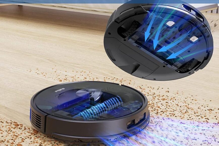 Een zwarte robotstofzuiger ligt op een houten vloer en verwijdert kruimels en stofdeeltjes. De afbeelding toont de krachtige zuigfunctie met visuele elementen die de luchtstroom aanduiden.