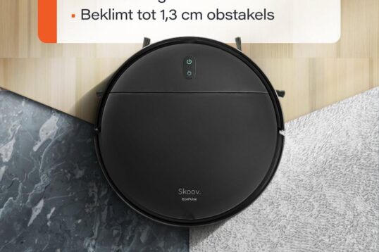 Een zwarte robotstofzuiger staat centraal op de afbeelding en is geplaatst op een overgang tussen verschillende vloertypes, waaronder een houten vloer en een marmeren vloer. Boven de stofzuiger staat een tekst met informatie over de veelzijdigheid en functie, zoals het automatisch aanpassen van de zuigkracht en de mogelijkheid om obstakels tot 1,3 cm te beklimmen.
