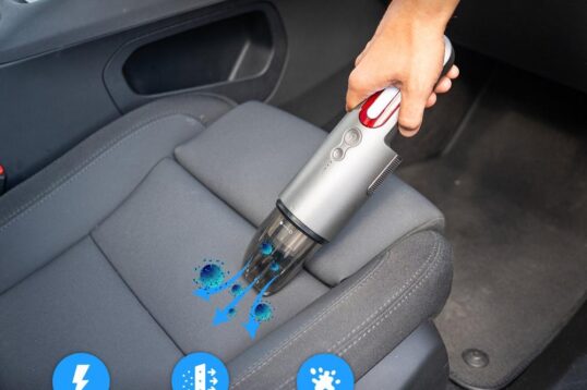 Draagbare stofzuiger in gebruik op een autobezitting, met een focus op het opzuigen van vuil en dierenhaar. De afbeelding benadrukt de krachtige motor en het gebruiksgemak voor het reinigen van kieren en moeilijk bereikbare plekken.
