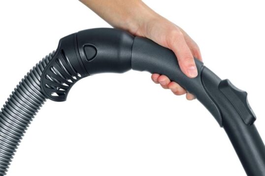 Afbeelding van een hand die de steel van een stofzuiger vasthoudt, met een focus op de ergonomische grip en het flexibele deel van de slang. Deze afbeelding illustreert de gebruiksvriendelijkheid en functionaliteit van de stofzuiger.
