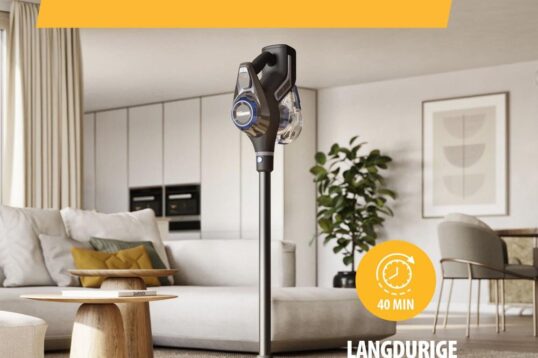 Afbeelding van een krachtige snoerloze stofzuiger in een moderne woonkamer. De stofzuiger is rechtop geplaatst naast een banken met een houten salontafel en planten op de achtergrond, met een focus op de lange batterijduur van 40 minuten.