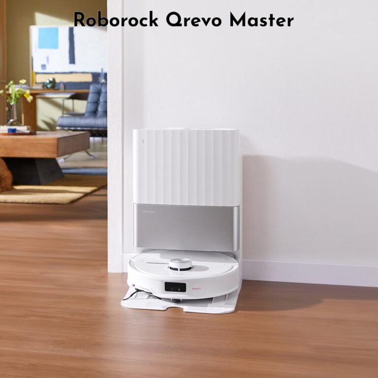 Afbeelding van de Roborock Qrevo Master robotstofzuiger, geplaatst op een houten vloer naast een wand. De stofzuiger staat voor een moderne woonkamer met meubilair op de achtergrond.