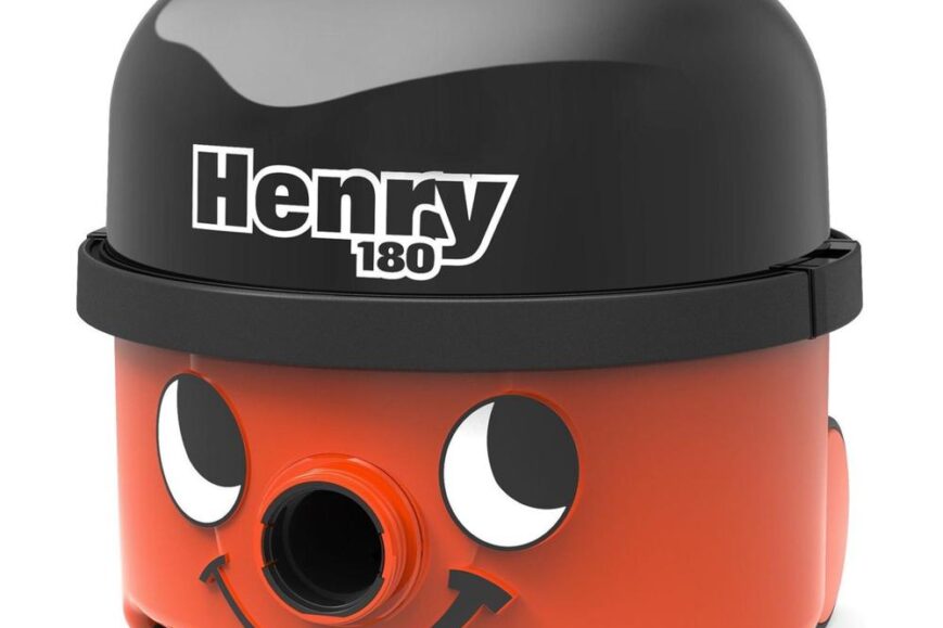 Een kleurrijke stofzuiger genaamd Henry 180, met een zwarte bovenkant en een vrolijke oranje onderkant die een lachend gezichtje heeft. De stofzuiger is uitgerust met een handvat en vier wielen voor gemakkelijke verplaatsing.