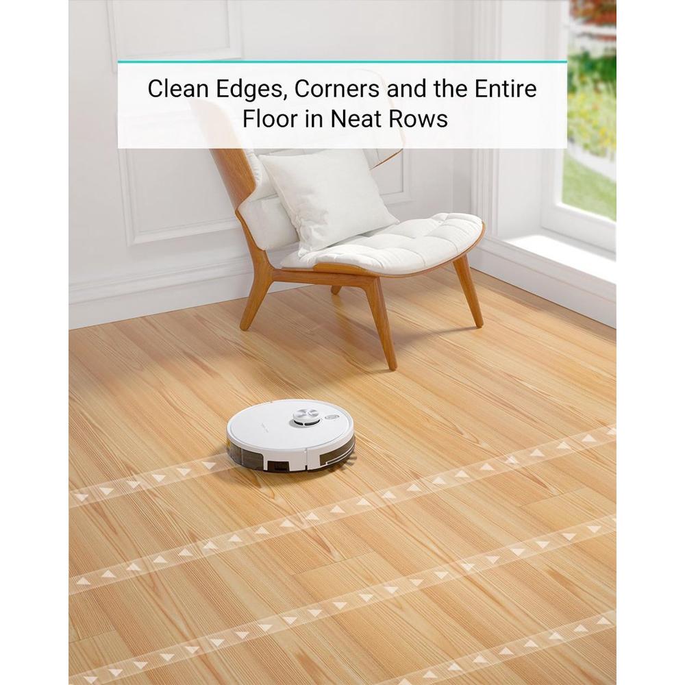 Een robotstofzuiger schoonmaakt een houten vloer, terwijl een comfortabele stoel op de achtergrond staat. De vloer toont nette schoonmaaksporen achtergelaten door de stofzuiger.