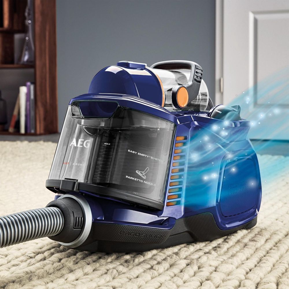 Een blauwe stofzuiger van AEG staat op een lichtgekleurd tapijt, met een doorzichtige stofcontainer en een flexibele slang. De afbeelding toont ook de 'Easy Empty' functie en benadrukt de krachtige zuigcapaciteit.