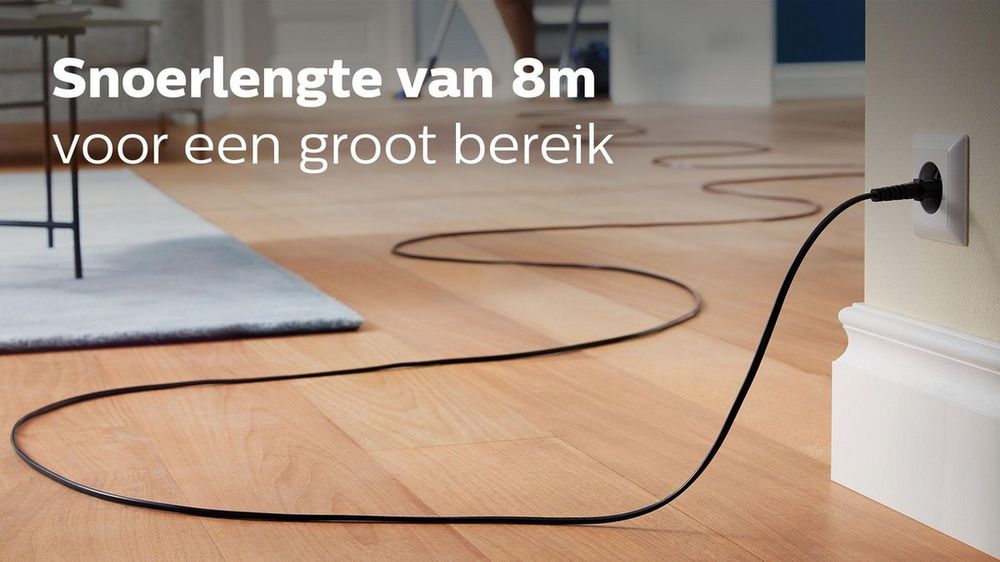 Een lange zwarte stroomkabel van 8 meter is weergegeven, die naar een wandcontactdoos leidt. De kabel ligt op een houten vloer en benadrukt de functionaliteit van een groot bereik voor elektrische apparaten.