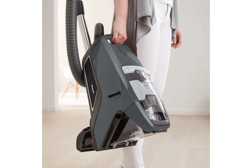 Miele Blizzard CX1 PowerLine stofzuiger in hand van gebruiker, klaar voor gebruik op houten vloer
